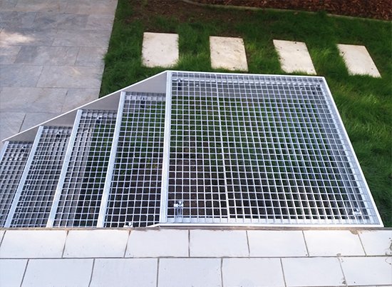 Escalera de zancas laterales y peldaños de trámex para acceso a jardín