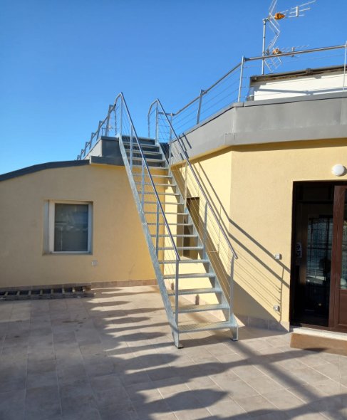 Escalera exterior en acero galvanizado para acceso a azotea.