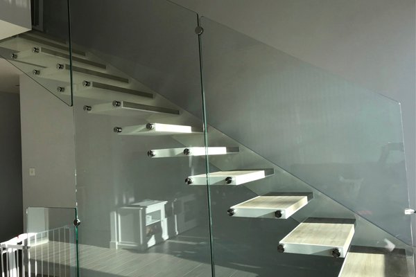 Escalera modelo «Arrietara»: autoportante con barandilla de vidrio y peldaños cerámicos.