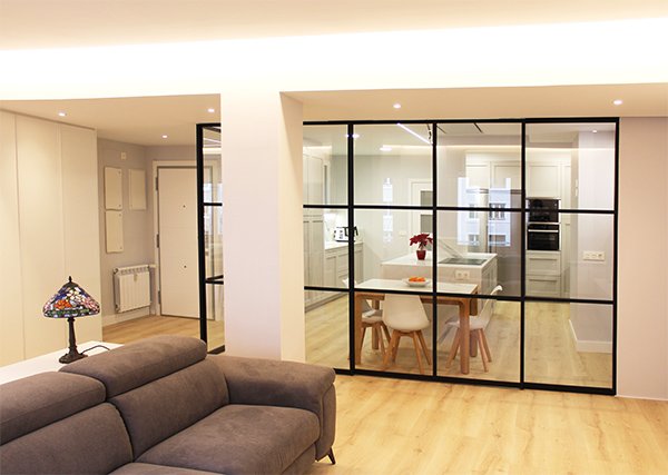 Mampara de acero y vidrio con puerta corredera para separación de salón y cocina.